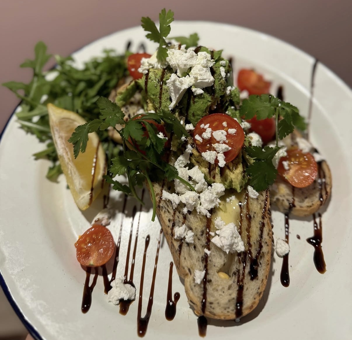 Smashed avocado on sourdough with feta, cherry tomatoes and balsamic glaze